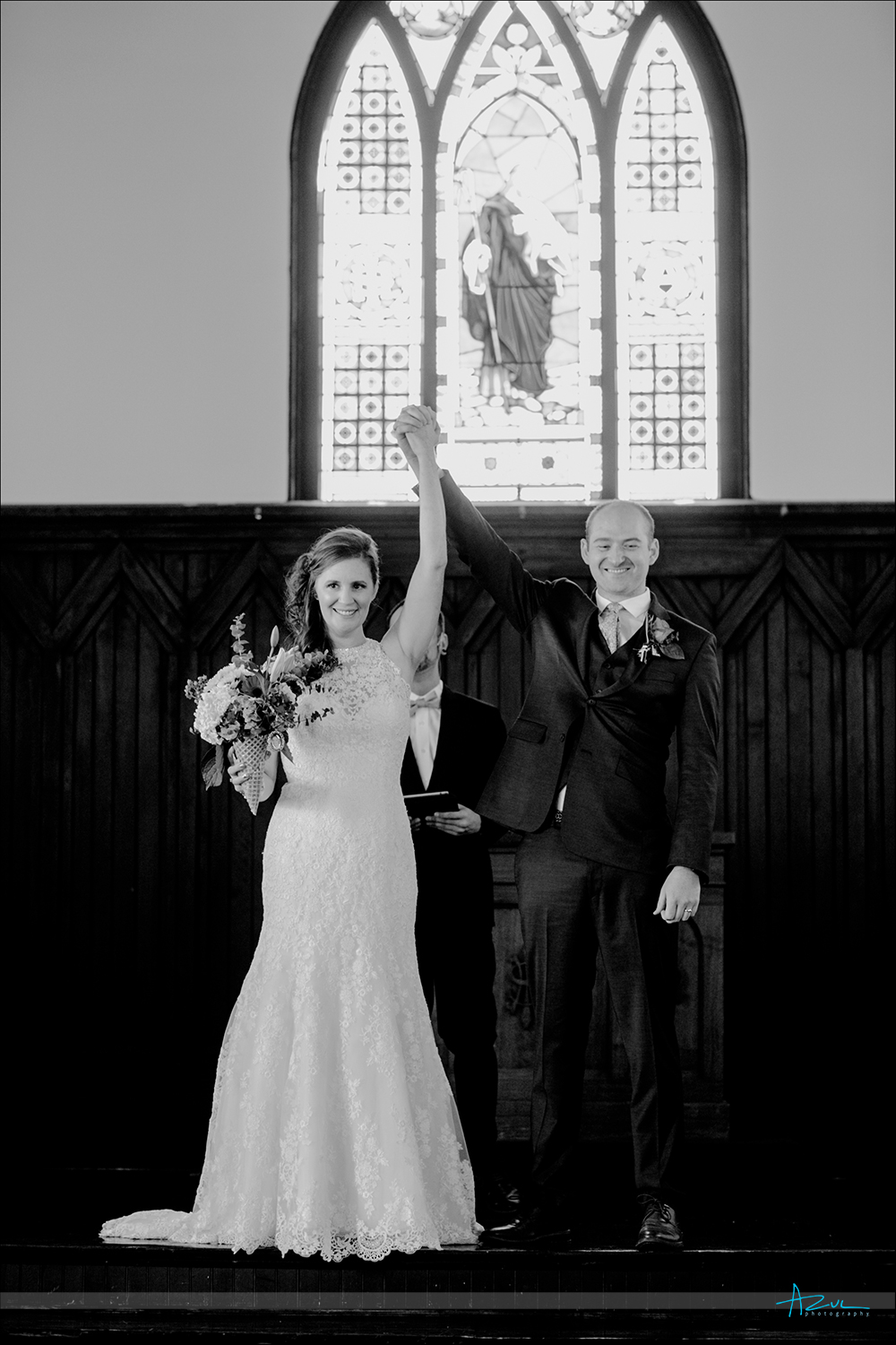 The bride and groom raise their arms in victory after the wedding as the photographer captured this perfectly in Raleigh NC